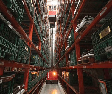 A red automated guided vehicle working in a busy warehouse.