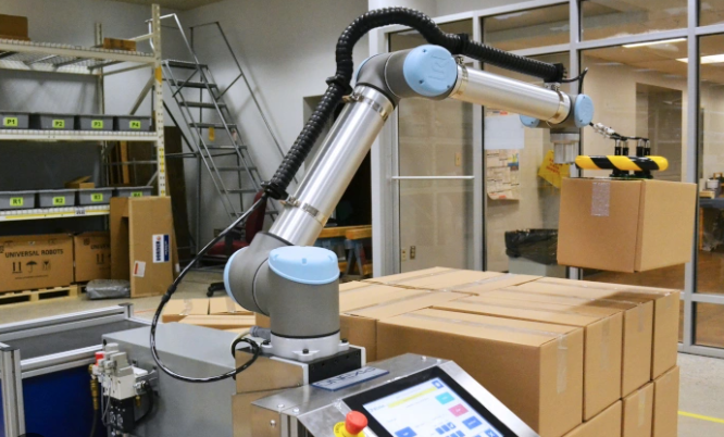 A grey cobot moving boxes in a warehouse.