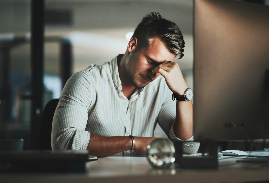 Operations manager holding his head in frustration, appearing overwhelmed and disappointed in a logistics warehouse setting.
