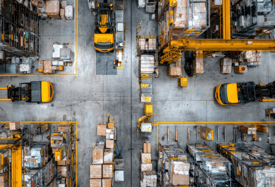 An aerial view of a modern warehouse with forklifts and organised storage aisles, illustrating efficient warehouse layout, material flow, and design optimisation achieved through peer review.