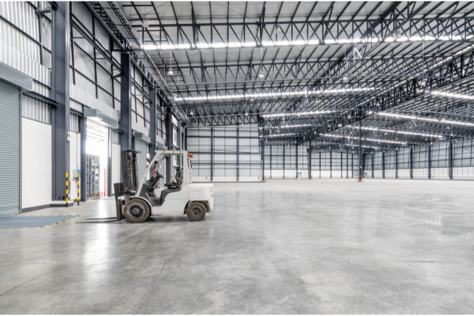 An empty warehouse aside from a forklift to show the challenges and opportunities when investing in a new warehouse